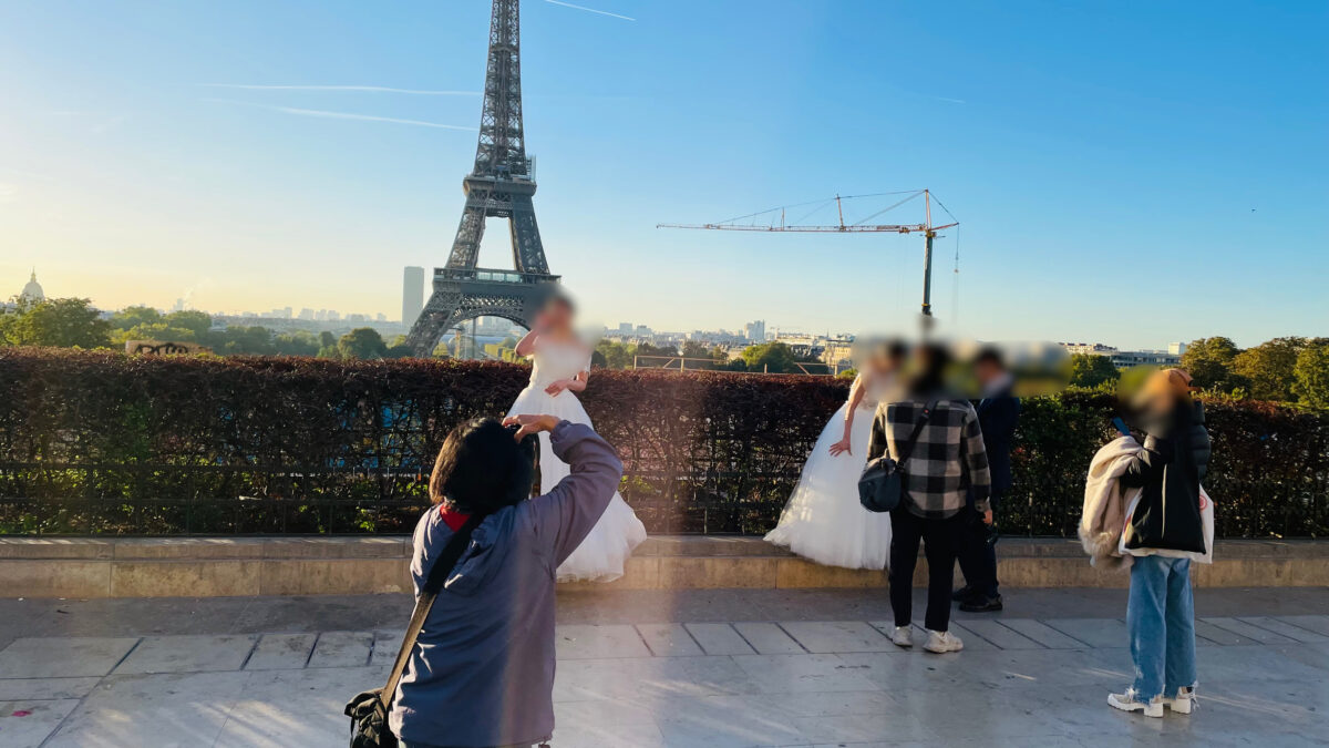 カメラマンがエッフェル塔を背景に撮影しているところ